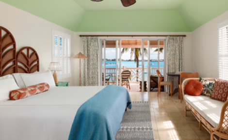 Ocean-view guest room with balcony and king bed at Cambridge Beaches Resort in Bermuda.