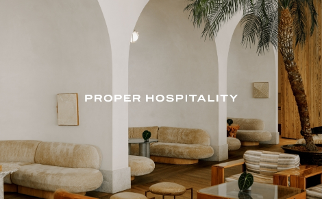 Lounge with arched walls, palm tree, and plush beige seating at Santa Monica Proper