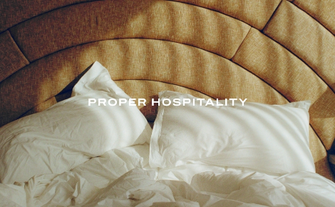 Cozy bed with white linens and curved tan headboard at Santa Monica Proper