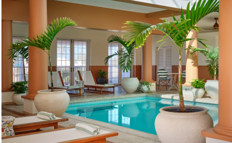 Indoor spa pool with lounge chairs and tropical plants at Cambridge Beaches Resort in Bermuda.