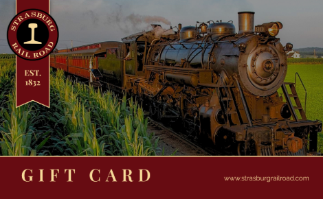 The image is a classic, nostalgic promotional graphic for a Strasburg Rail Road gift card. It features a prominent photograph of a vintage black steam locomotive, engine number 90, puffing smoke as it cuts through vibrant green cornfields under a soft sunset. A deep maroon banner on the left display