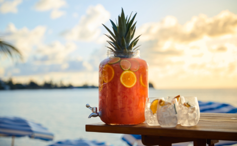 Tropical punch dispenser with citrus and pineapple served by the ocean at Cambridge Beaches in Bermuda.