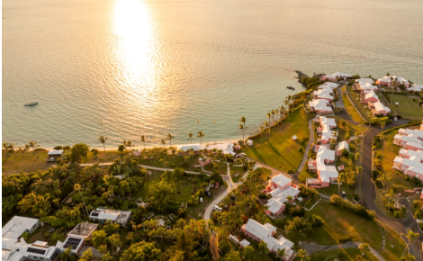 Aerial view of Cambridge Beaches Resort in Bermuda at sunset along the ocean coastline.