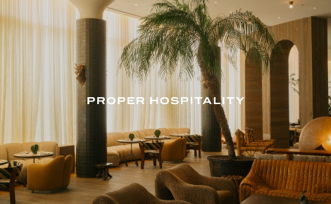 Lounge with curved seating, palm tree, and warm neutral tones at Santa Monica Proper