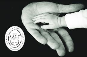Image of a child's hand in an adults hand with the Salt Factory Pub logo