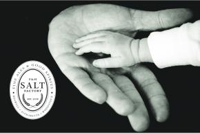 Image of a baby's hand touching an adults hand with the Salt Factory logo