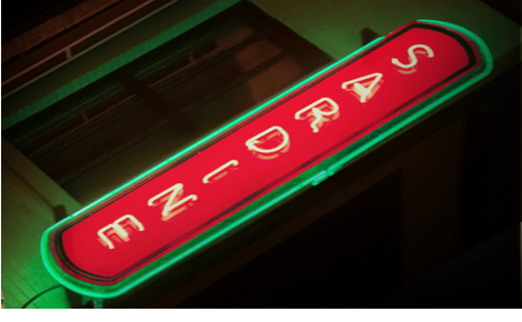 Iconic red and green “sardine” neon sign, lit up at night with a moody black and green background