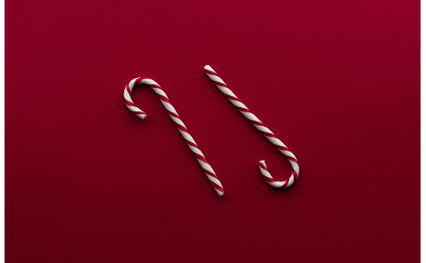 Two candy canes on dark red background.