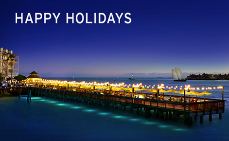 Gift card image of the pier at night with the seating area all lit up and the text “Happy Holidays”