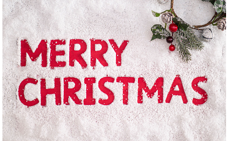 Red Merry Christmas letters written with a finger in snow with a wreath in top right corner.