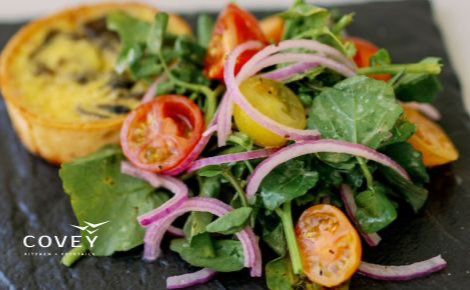 This image is of a colorful salad and a small baked quiche. This is promoting Covey Kitchen + Cocktails. 
