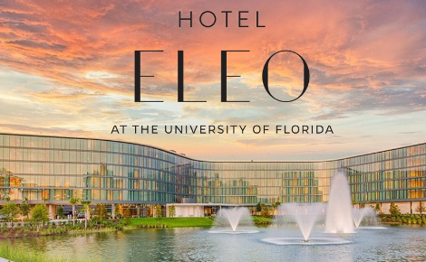 A shot of Hotel ELEO's long winding glass exterior, Covey, and the fountains of Lake Rush. 